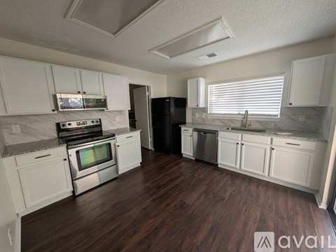 A kitchen with white cabinets and a black refrigerator.