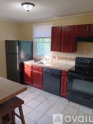 A kitchen with a black refrigerator, black oven, and black microwave.