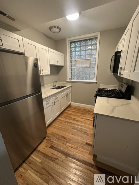 A kitchen with a stainless steel refrigerator and wooden floors.
