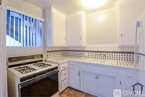 A kitchen with white cabinets and a stove top oven.