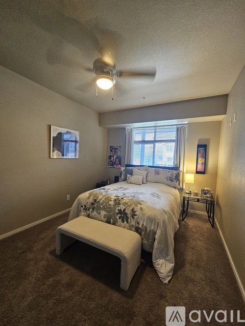 A bedroom with a bed, a bench, and a ceiling fan.