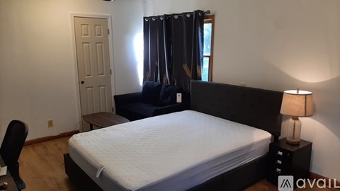 A bedroom with a large bed, a chair, and a lamp.