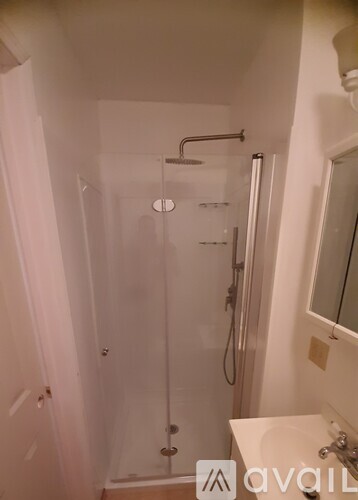 A bathroom with a glass shower stall and a white sink.
