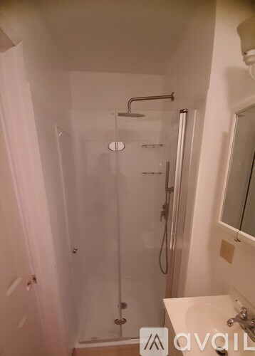 A bathroom with a glass shower stall and a white sink.