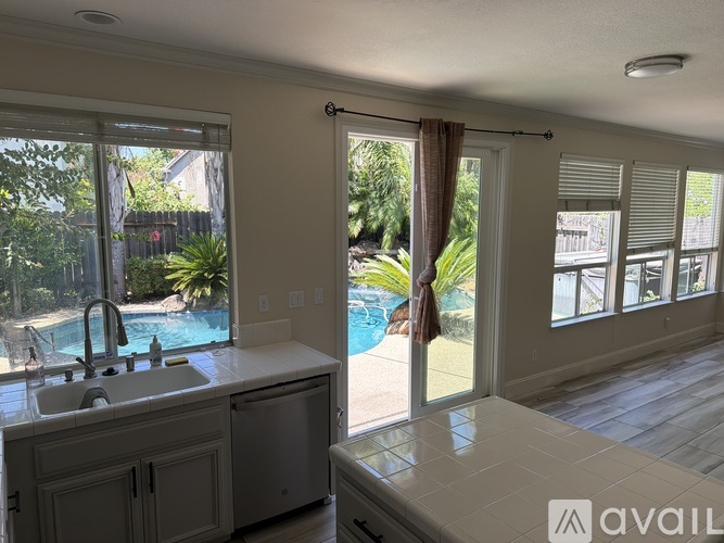 A kitchen with a sink and a pool in the backyard.