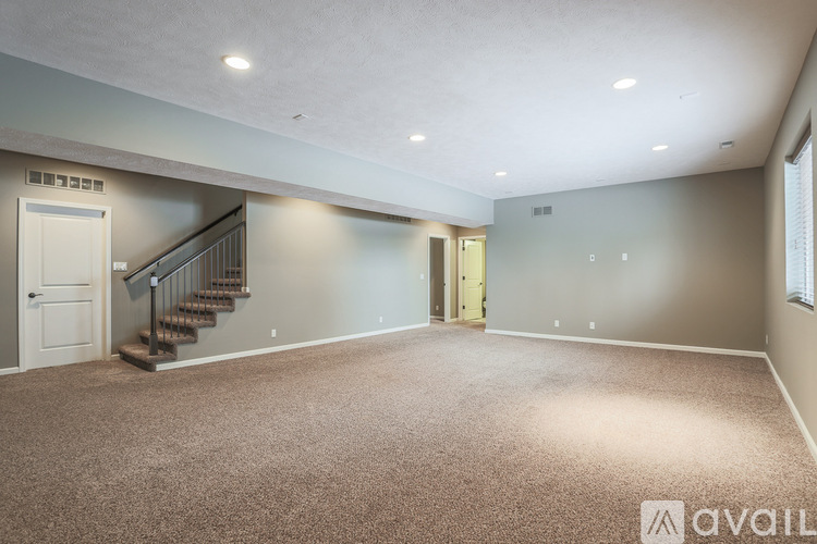 A spacious room with a staircase and a carpeted floor.