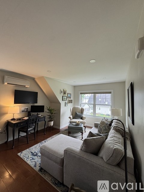 A living room with a grey couch and a television on the wall.