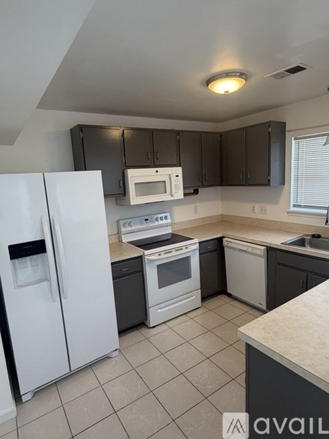 A kitchen with white appliances and black cabinets.