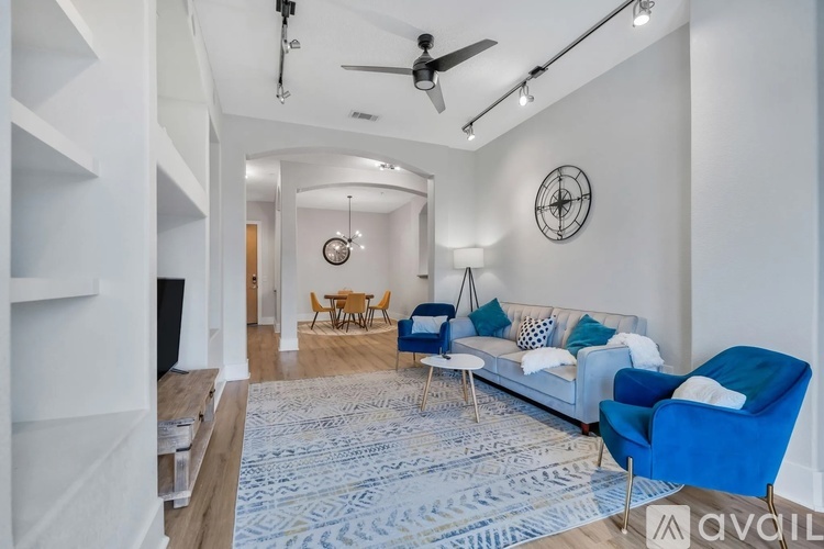 A living room with a white couch, blue chairs, and a rug.