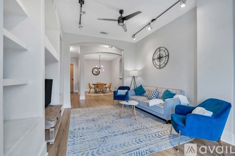 A living room with a white couch, blue chairs, and a rug.