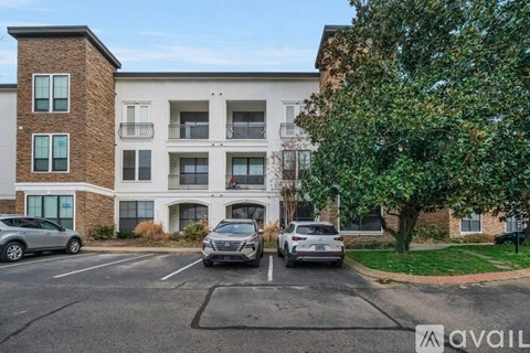Two cars are parked in a parking lot in front of a multi-story apartment building.