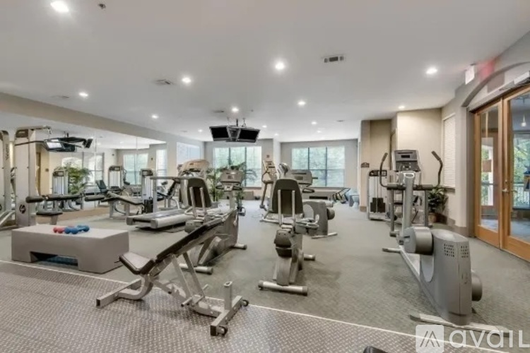 A spacious gym with various exercise equipment and a television mounted on the wall.