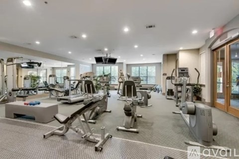 A spacious gym with various exercise equipment and a television mounted on the wall.