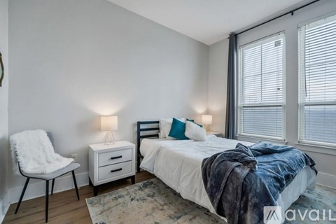 A bedroom with a bed, chair, and two lamps.