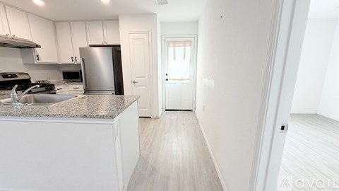 A kitchen with white cabinets and a stainless steel refrigerator.