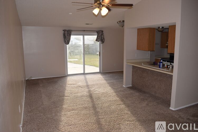 A living room with a carpeted floor and a ceiling fan.