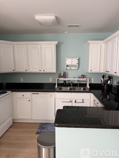 A kitchen with white cabinets and a black countertop.