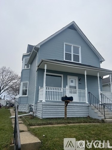 A blue house with a white porch and a mailbox on the front.