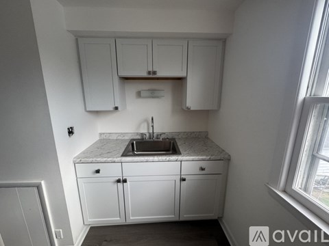 A kitchen with white cabinets and a marble countertop.
