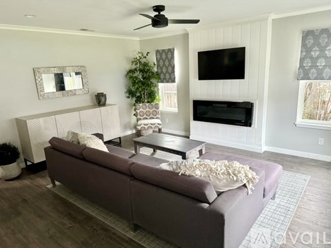 A living room with a grey couch and a white pillow.