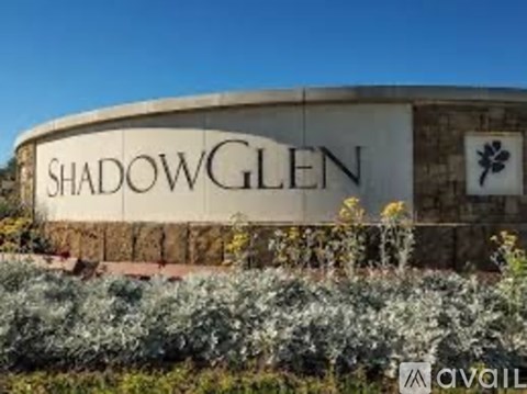 A sign that says ShadowGlen in front of some bushes.