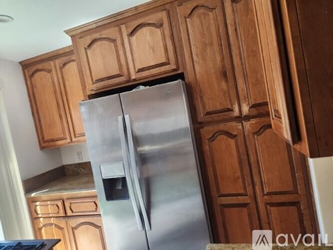 A stainless steel refrigerator with a digital display is in a kitchen with wooden cabinets.