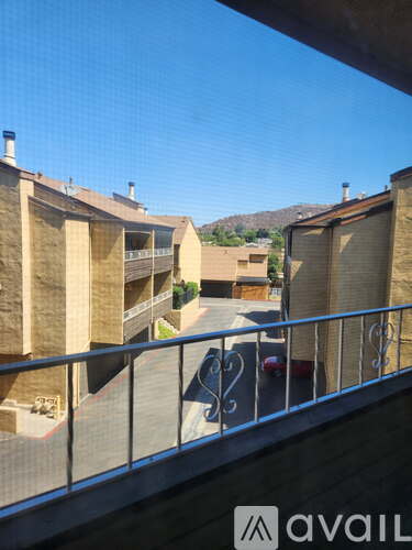 A view from a balcony overlooking a parking lot and buildings.