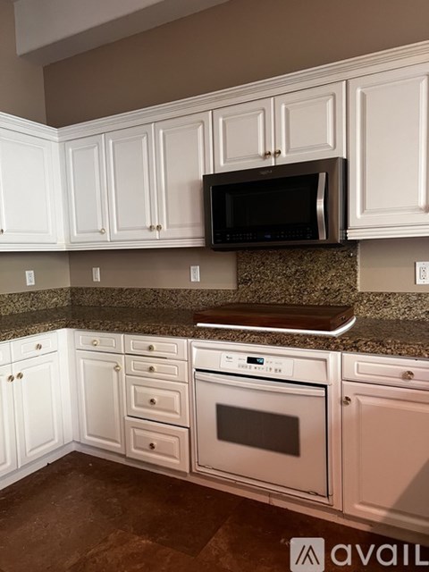 A kitchen with white cabinets and a granite countertop.