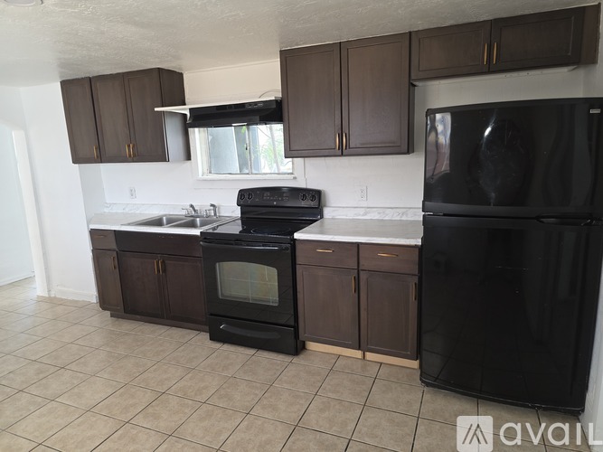 A kitchen with brown cabinets and black appliances.