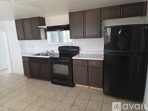 A kitchen with brown cabinets and black appliances.
