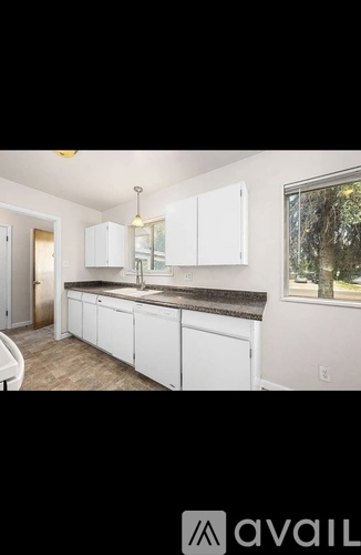 A kitchen with white cabinets and a window.