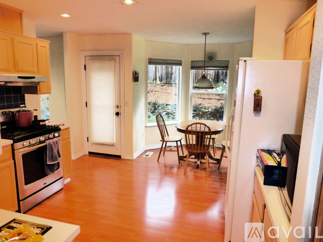 A kitchen with a stove, refrigerator, and a dining table with chairs.