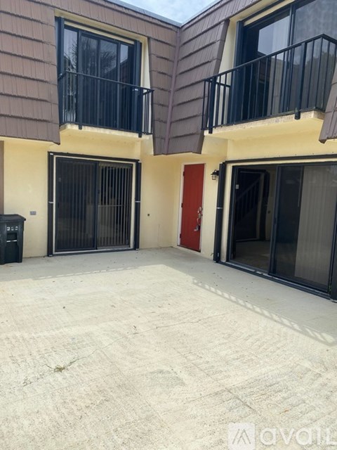 A balcony with a black railing and a red door is visible.