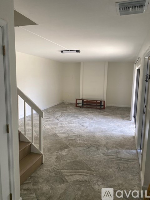A room with a stone floor and a staircase leading to the upper floor.