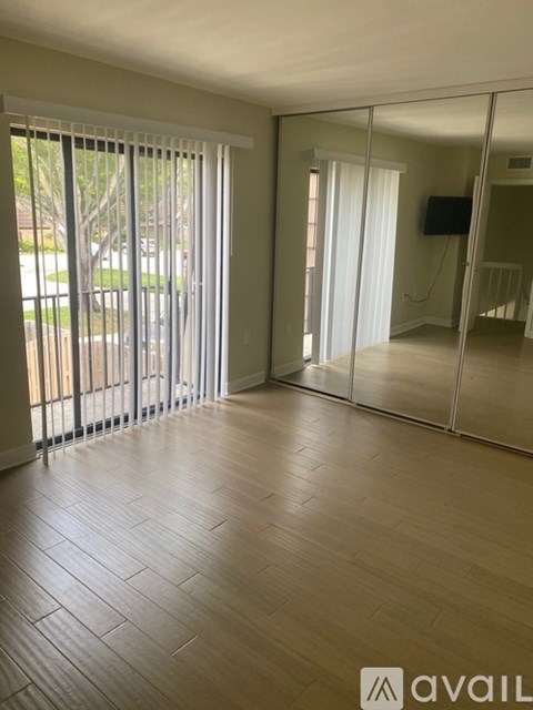 A spacious room with a sliding glass door and wooden flooring.