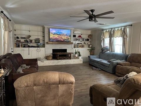 A living room with a brown couch, a chair, and a television on the wall.