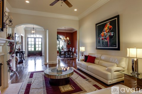A living room with a white couch and a painting on the wall.