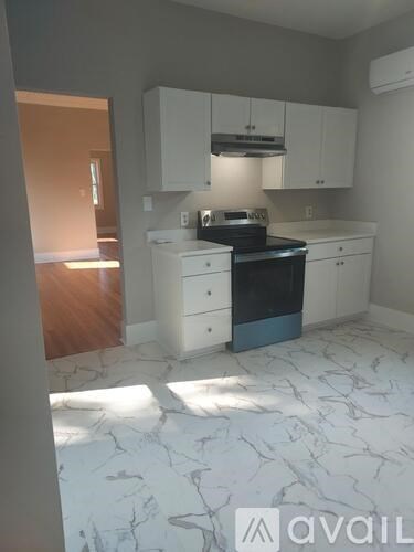A kitchen with white cabinets and a marble floor.