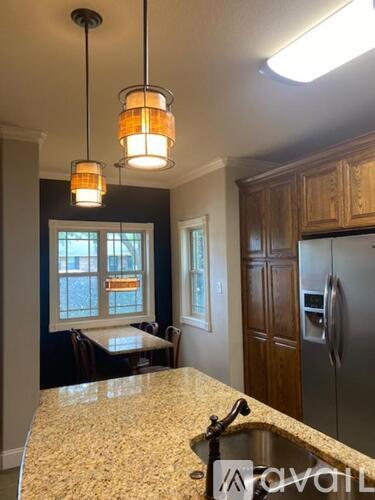 A kitchen with a granite countertop and wooden cabinets.