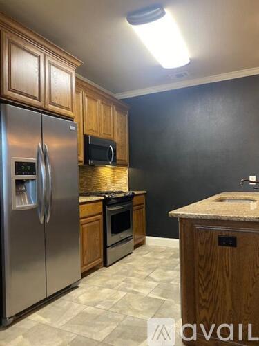A kitchen with a refrigerator, microwave, oven, and sink.