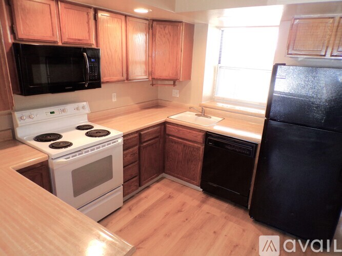 A kitchen with wooden cabinets and a black fridge.