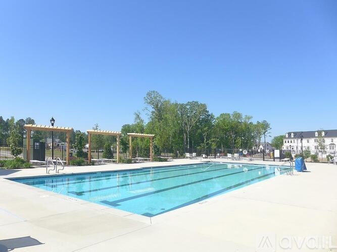 A large outdoor swimming pool surrounded by trees and a building in the background.