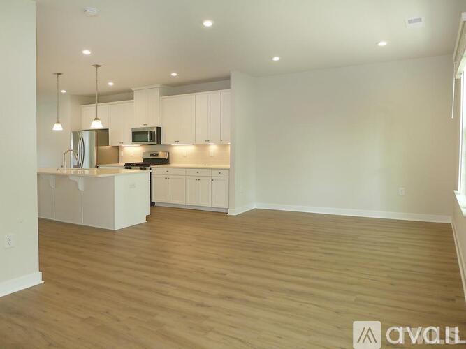 A kitchen with white cabinets and a wooden floor.