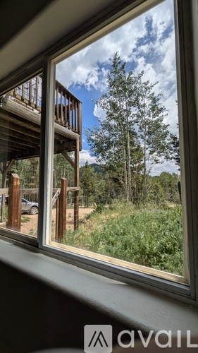 A window with a view of a wooden deck and trees.