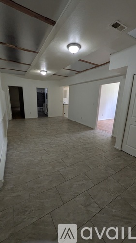 A spacious room with a tiled floor and a ceiling with exposed beams.