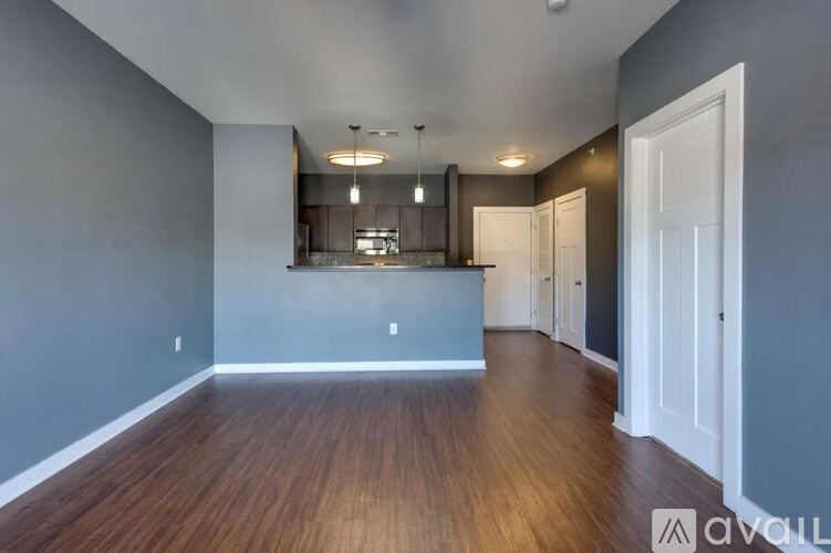 A spacious room with wooden flooring and a large mirror on the wall.