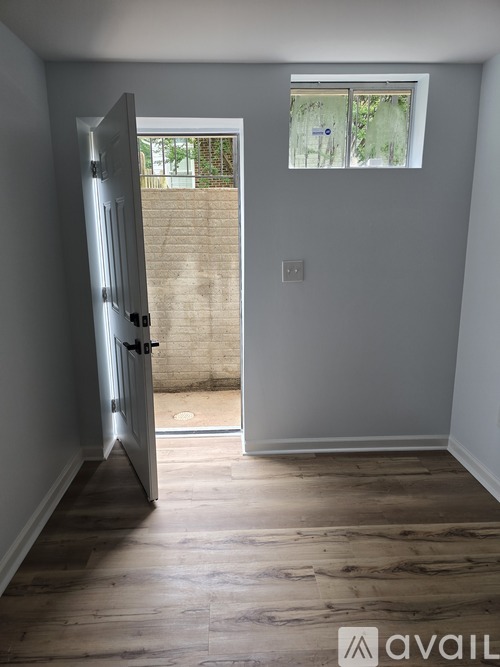 A room with a wooden floor and a door leading to a balcony.