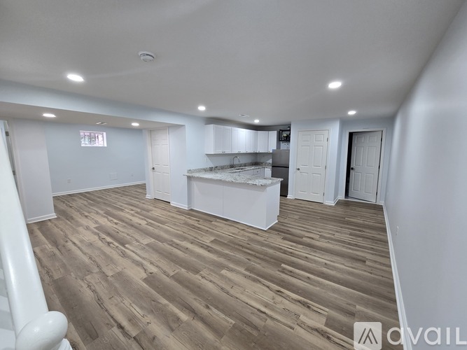 A spacious room with wooden flooring and white walls.