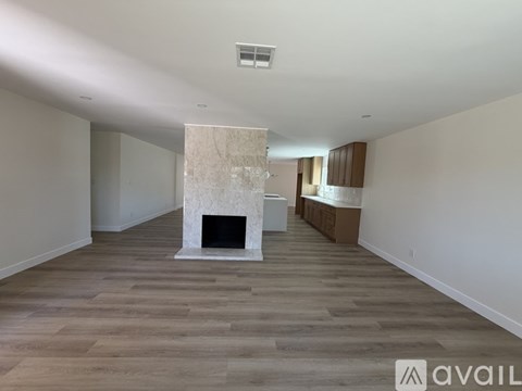 A spacious room with a fireplace and wooden flooring.