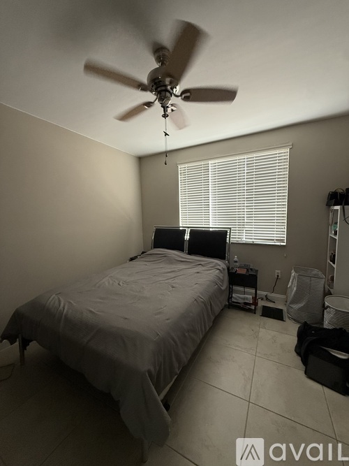 A bedroom with a bed, a ceiling fan, and a window with blinds.